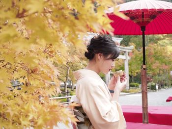 Woman holding umbrella while standing by flowering plants