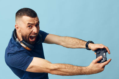 Portrait of young man exercising against blue background