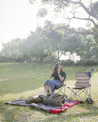 Woman sitting on grass against trees