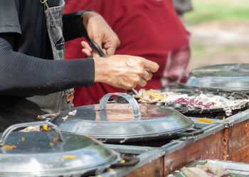 Midsection of man preparing food on barbecue grill