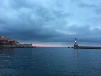 Lighthouse on sea against buildings