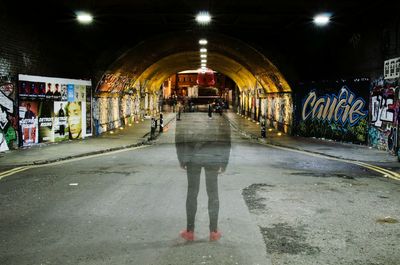 Rear view of woman walking in illuminated city at night