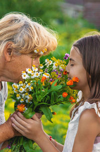 Side view of smiling friends holding flowers