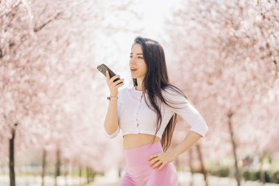 Midsection of woman holding cherry standing by tree