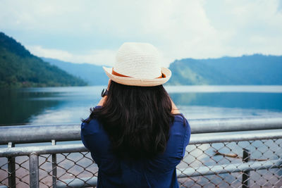 Rear view of woman looking at view of sea standing by railing