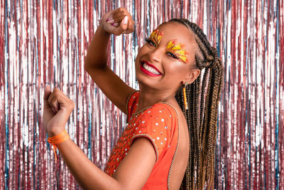 Portrait of young woman standing against wall