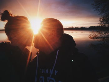 Close-up of couple kissing against river during sunset