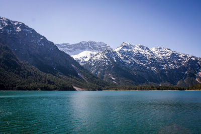 Scenic view of lake and snowcapped mountains against clear blue sky