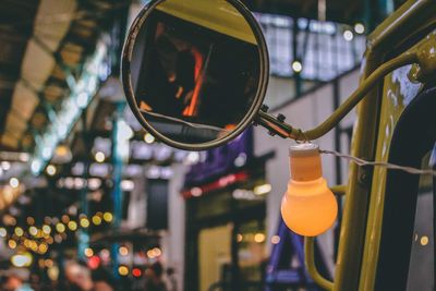 Side-view mirror of vehicle in illuminated city at night