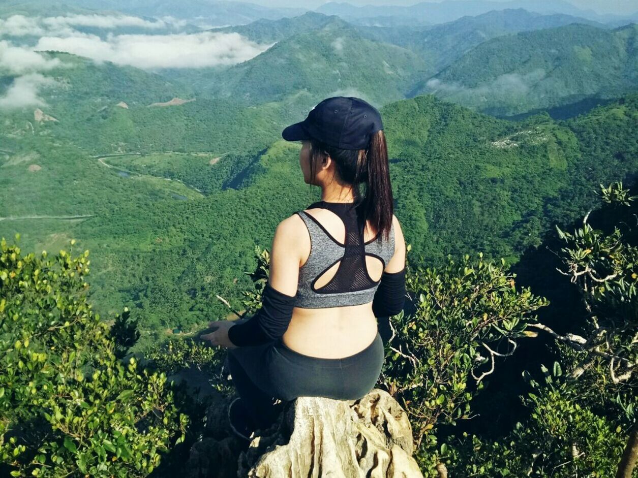 REAR VIEW OF WOMAN STANDING ON MOUNTAIN