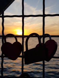 Close-up of silhouette plants against sea during sunset