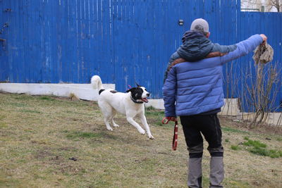 Rear view of man with dog in garden 