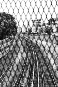 Railroad tracks in city seen through chainlink fence