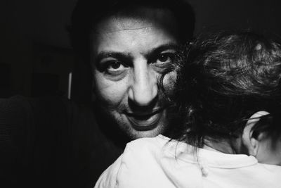 Close-up portrait of man with baby in dark