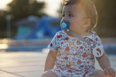 Close-up of cute baby boy with pacifier in mouth during sunset