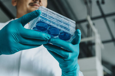 Scientist holding petri dish tray while standing at laboratory