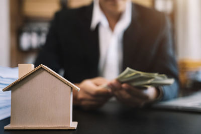 Midsection of businessman holding model home