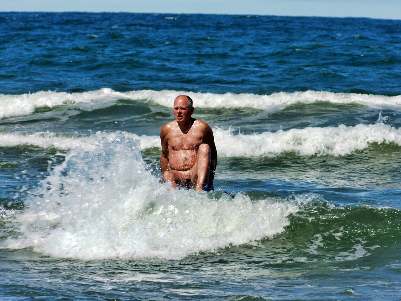 sea, water, wave, shirtless, motion, waterfront, leisure activity, surfing, people, sport, lifestyles, day, beauty in nature, men, aquatic sport, nature, real people, land, outdoors, horizon over water, power in nature