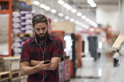 Male customer listening music through smart phone at hardware store