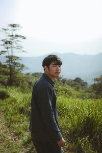 Young man standing on field against sky