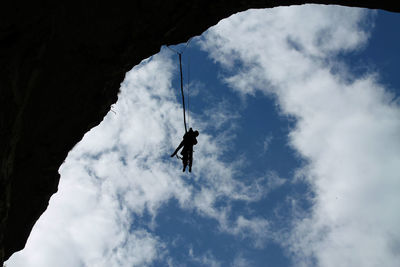 Low angle view of silhouette man paragliding against sky