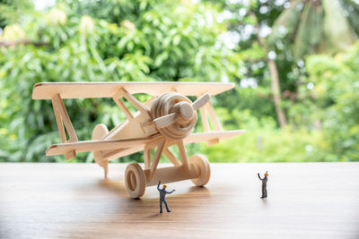 Close-up of figurines and model airplane on table with trees in background