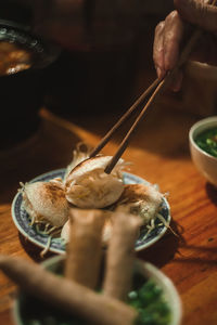 Cropped hand of person holding food in plate on table