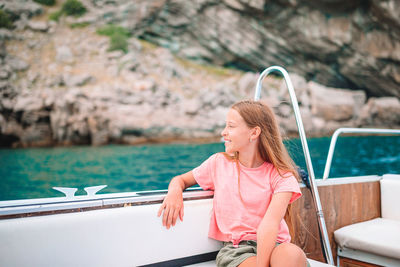 Smiling girl sitting on boat in sea