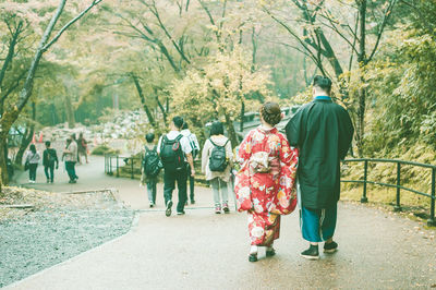 Rear view of people walking on footpath in park