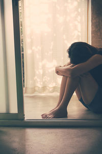 Side view of depressed woman sitting at home