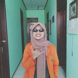 Portrait of smiling young woman standing against door