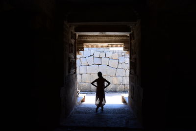 Rear view of silhouette man standing against building