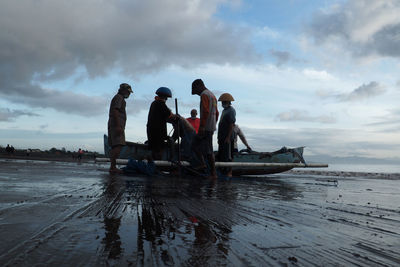 People standing by sea against sky