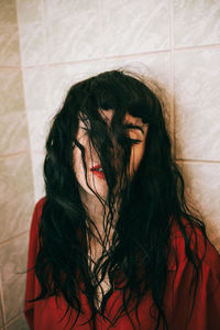 Close-up of young woman by tiled wall in bathroom