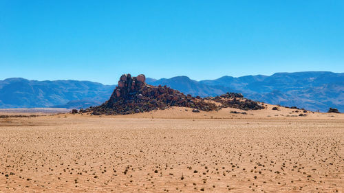 Scenic view of desert against clear blue sky