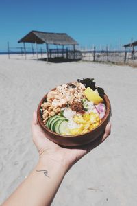 Midsection of person holding ice cream cone on beach