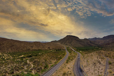 Road leading towards mountains against sky during sunset
