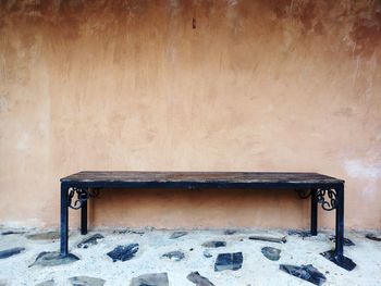 Empty bench on table against wall