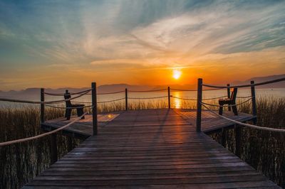 Pier leading towards sea during sunset