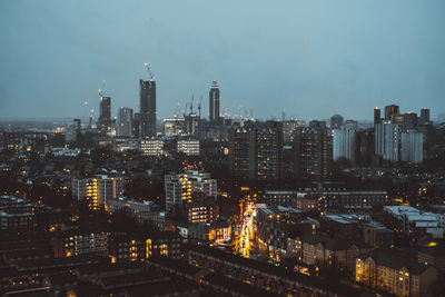 Illuminated modern buildings in city against sky