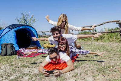 Young boys and girls in campsite piled up smiling