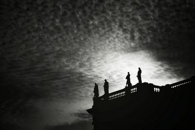 Low angle view of silhouette building against cloudy sky