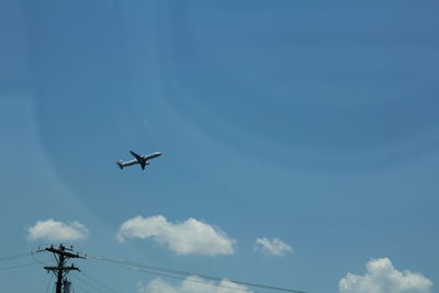 Low angle view of airplane against blue sky