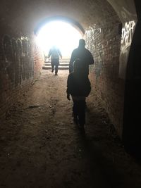 Rear view of people walking in tunnel