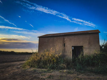 Abandoned building on field against sky during sunset