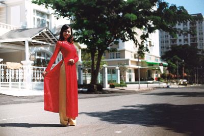 Young woman wearing red dress while standing on road