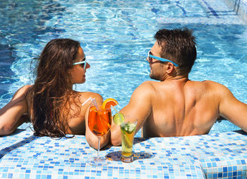 Rear view of smiling young woman swimming pool