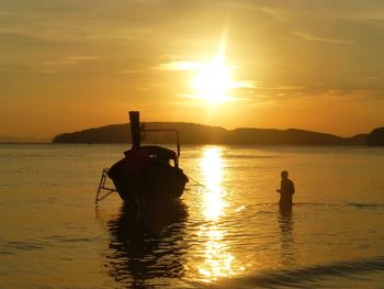 Silhouette man sailing on sea against sky during sunset