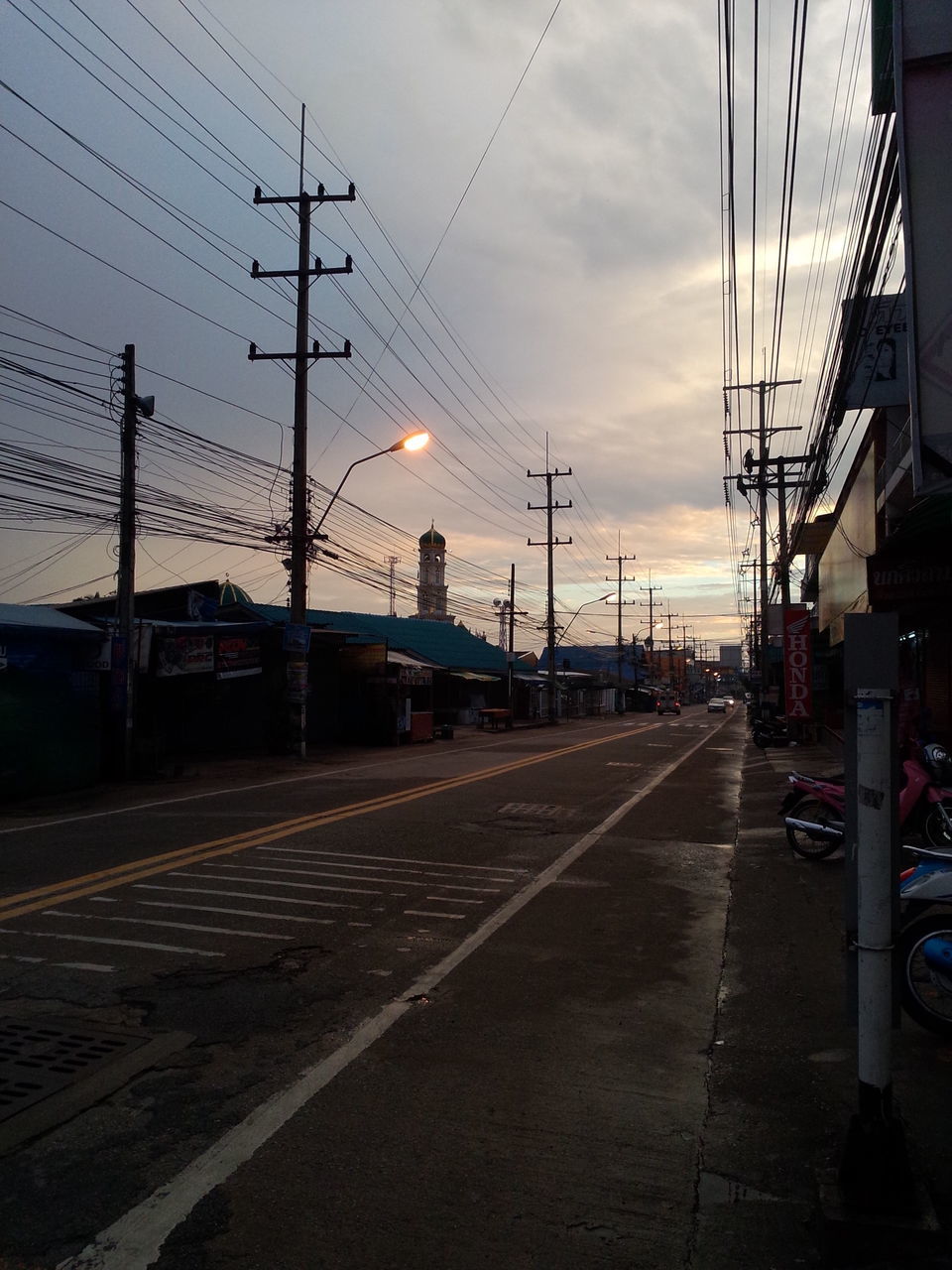 transportation, mode of transport, sky, building exterior, built structure, power line, electricity pylon, architecture, railroad track, land vehicle, city, cloud - sky, street, sunset, high angle view, connection, cable, dusk, electricity, power supply