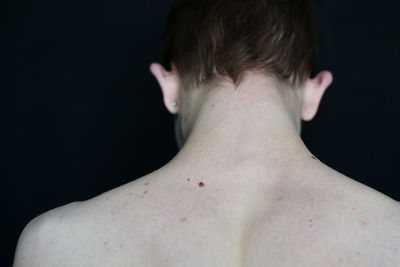 Rear view of shirtless man against black background